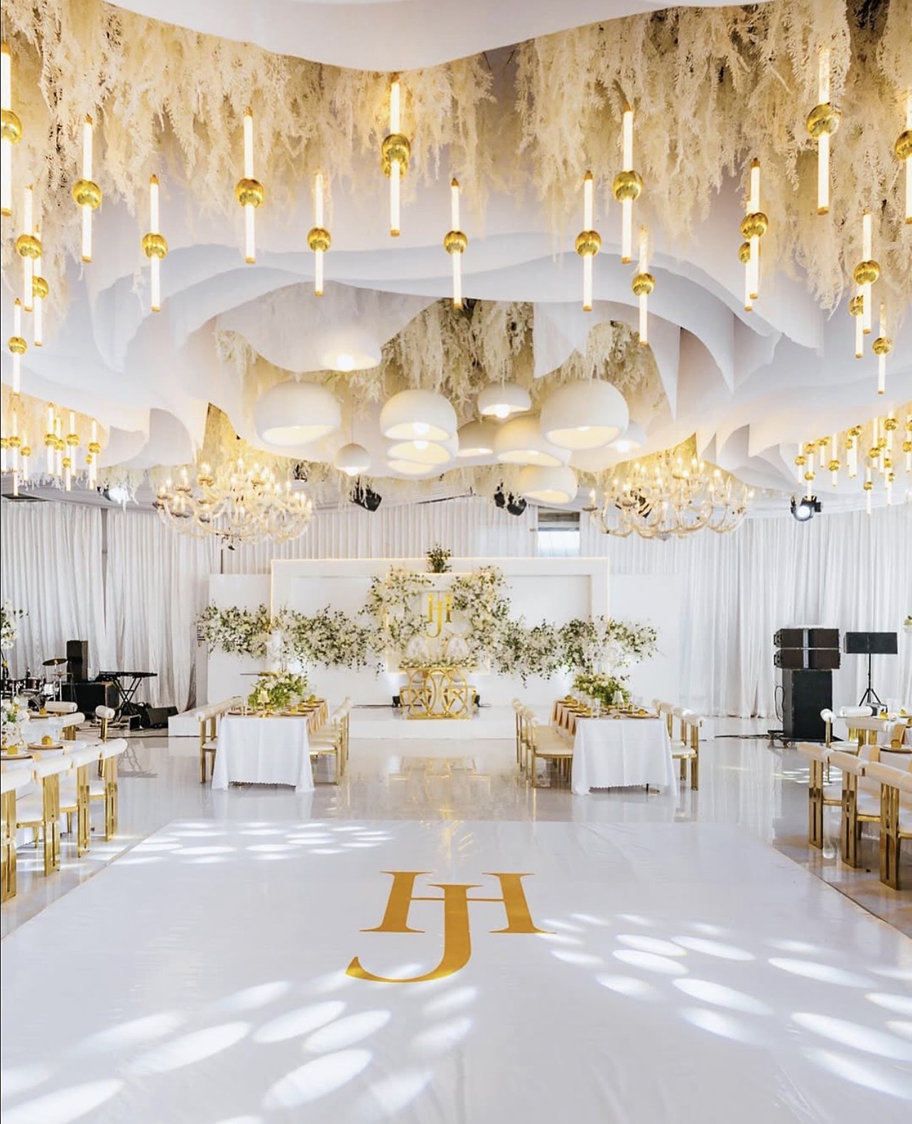 Dance floor with gold monogram beneath a ceiling of pampas, drapery and hanging candles