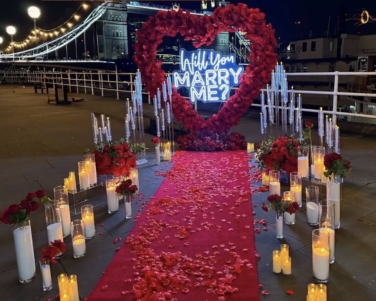 Waterfront proposal with a rose heart, Will You Marry Me neon and candles at night