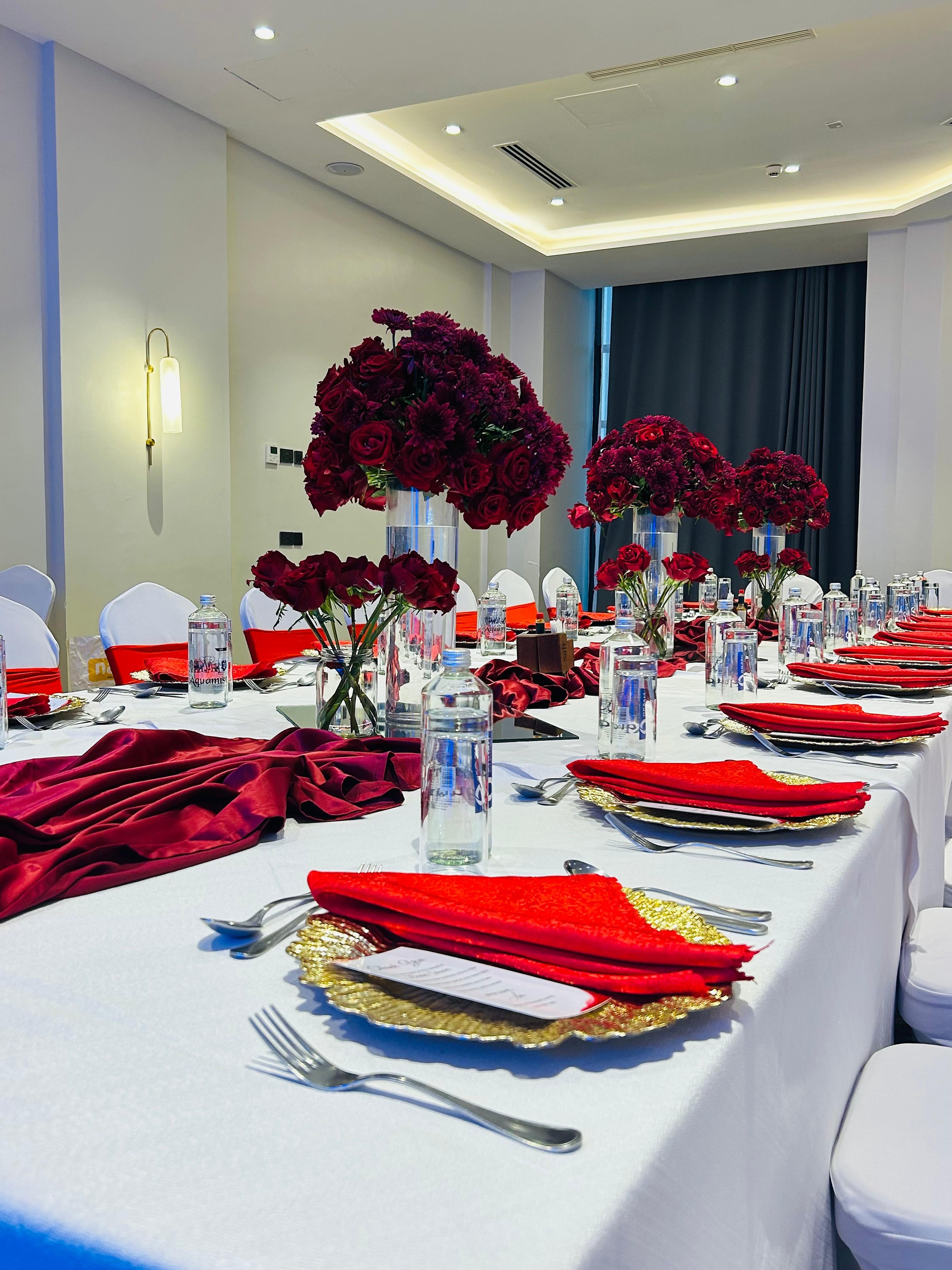 Banquet table with red velvet runners, red napkins and red rose centrepieces in a hotel hall